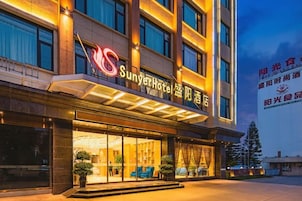 A hotel with a prominent sign, large windows, and a covered entrance area.