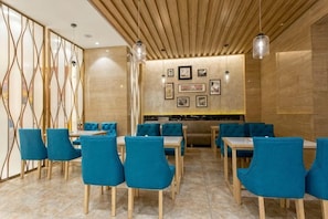 A restaurant with blue upholstered chairs, wooden tables, and a wooden ceiling. - Shengyang Hotel (Yuxi)