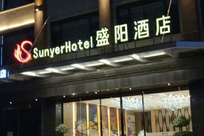 Entrada de hotel con señalización iluminada, amplias ventanas y diseño moderno.