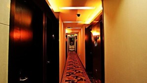 Pasillo de hotel con alfombra estampada, una cámara de seguridad y una puerta al final.