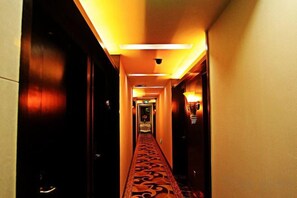Een hotelgang met een patroon in de vloerbedekking, deuren aan weerszijden en verlichting in het plafond.