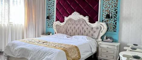 A bed with a white headboard and a gold accent, a nightstand with a lamp, and a blue decorative panel.