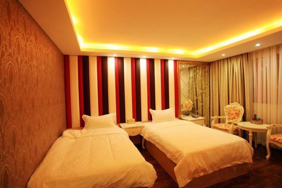 Une chambre d’hôtel avec deux lits, une petite table, une chaise et un miroir.