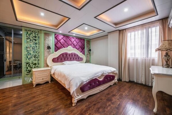 Un dormitorio con cama, mesita de noche, cómoda, cabecera decorativa y ventana con cortinas.