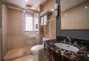 Une salle de bain avec une douche à parois de verre, des toilettes, un lavabo avec un plan de toilette en marbre et un porte-serviettes.