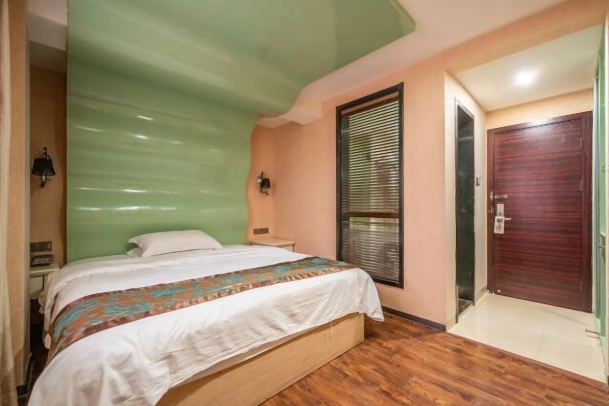 Une chambre à coucher avec un lit, une fenêtre avec des stores, une porte en bois et un plafond vert.