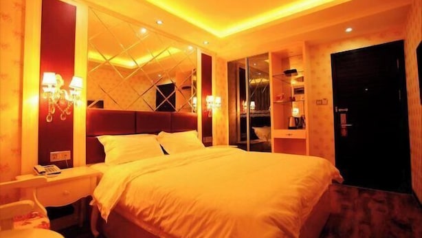 Una habitación de hotel con una cama grande, mesitas de noche, un escritorio y un armario.