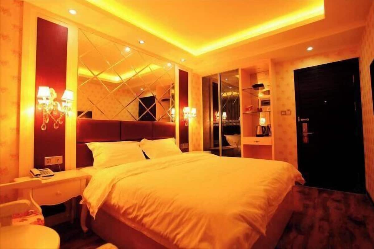 Une chambre d’hôtel avec un grand lit, des tables de chevet, un bureau et une armoire.