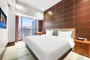 Una habitación de hotel moderna con una cama grande, cabecera de madera, mesita de noche y vistas a la ciudad.