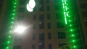 A building with a series of windows and a large, illuminated sign. - Green Leaf Inn (Dongguan)