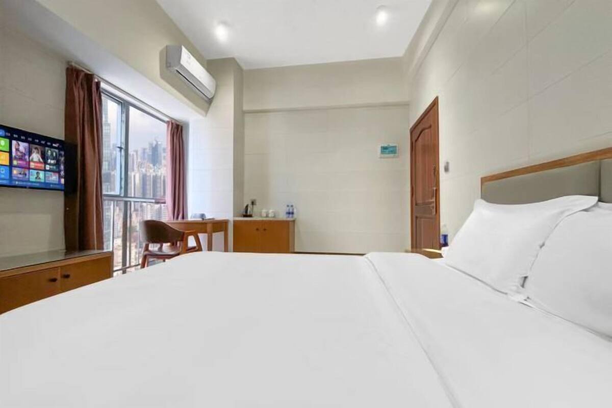Habitación de hotel con una cama grande, un escritorio, una silla y un televisor montado en la pared.