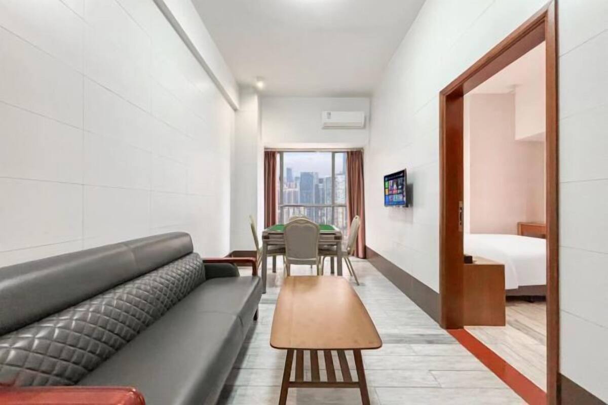 Habitación de hotel con sofá, una mesa de comedor, televisión y vistas a la ciudad.