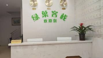 A reception desk with a clock, a potted plant, and a sign.