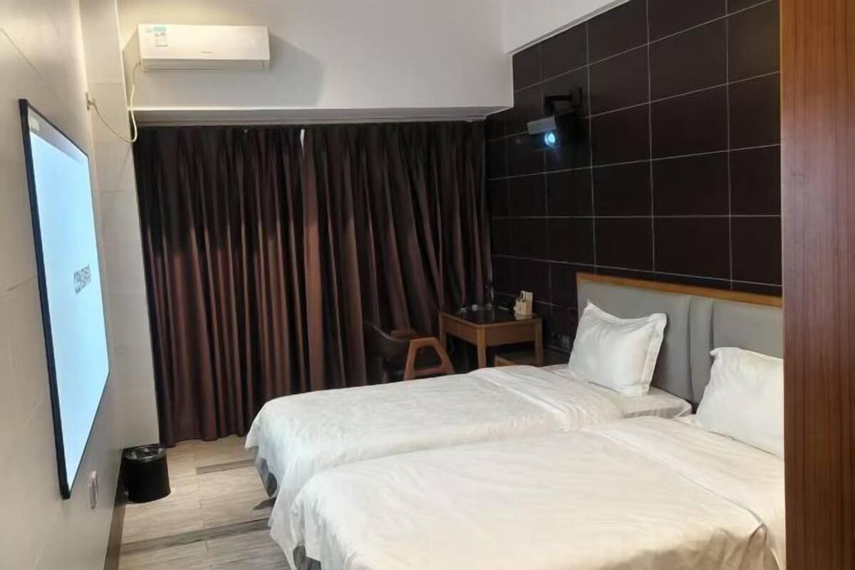 Una habitación de hotel con dos camas, un escritorio, una silla, un televisor y una cortina.