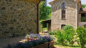 A stone building with a garden in front, a covered area, and a small window. - Villa Comunalia by MMega (Umbertide)