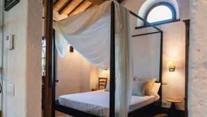 A four-poster bed with a canopy, a small bedside table, a chair, and a round table. - Villa Comunalia by MMega (Umbertide)
