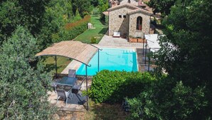 A stone building with a swimming pool, surrounded by lush greenery. - Villa Comunalia by MMega (Umbertide)