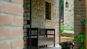 A stone wall with a bench, a potted plant, and a hanging lantern. - Villa Comunalia by MMega (Umbertide)