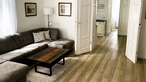 A living room with a sofa, coffee table, and a door leading to a kitchen. - Large stylishly furnished holiday flat in a quiet and central location (Weimar)