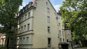 A multi-story building with a beige facade, a stone entrance, and a small garden area. - Large stylishly furnished holiday flat in a quiet and central location (Weimar)