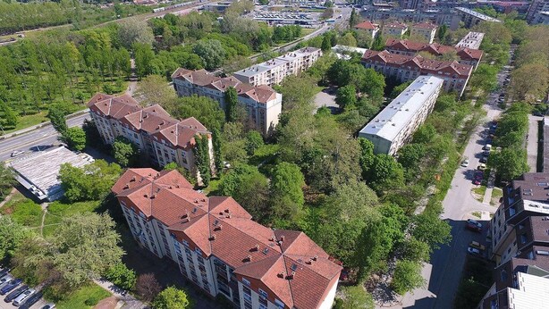 Vue aérienne d’un quartier résidentiel avec des immeubles à plusieurs étages, des rues et des espaces verts.