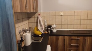 Une cuisine avec des meubles en bois, un plan de travail noir et un pare-feu en carrelage.