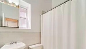 Un baño con lavamanos, inodoro y cortina de ducha.