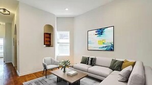 Una sala de estar moderna con sofá, sillón, mesa de centro y un cuadro en la pared.