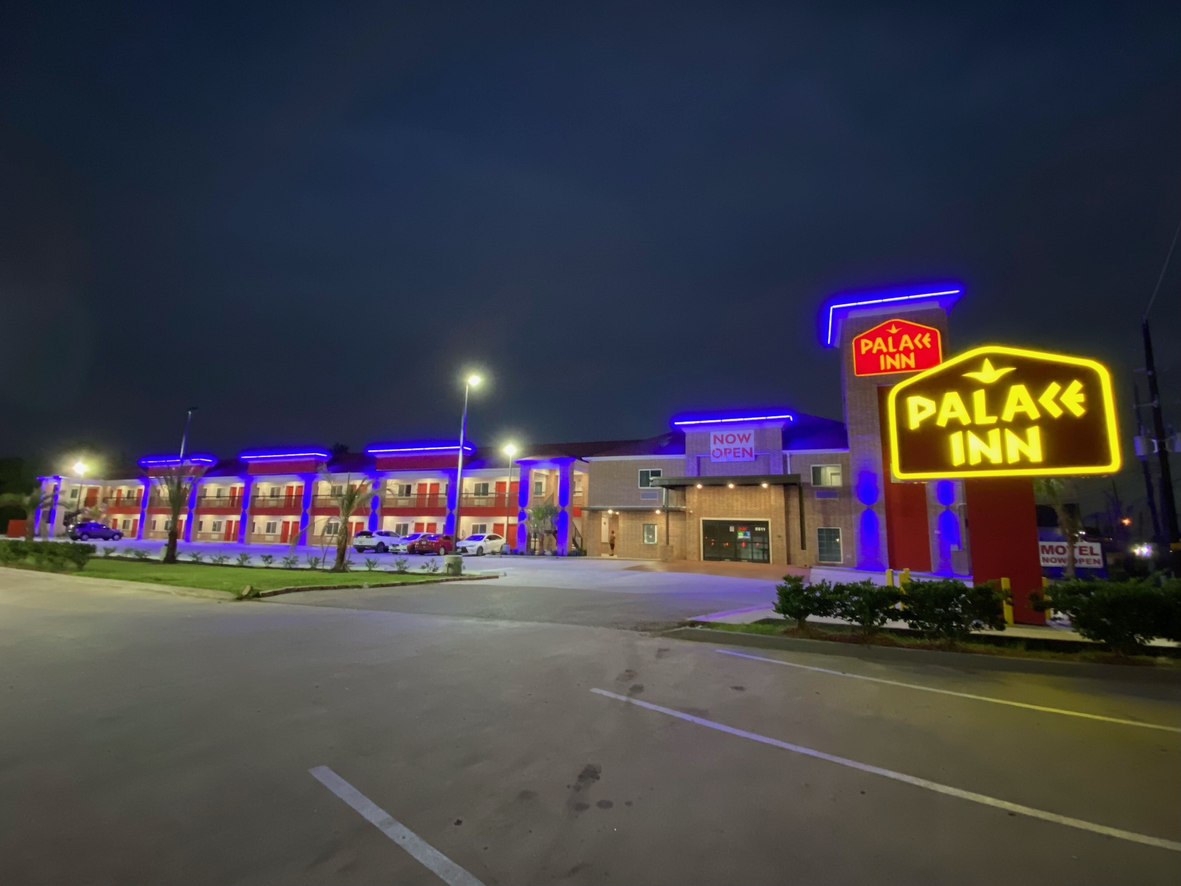 A hotel named "Palace Inn" with a neon sign, multiple parking spaces, and a well-lit entrance.