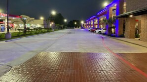 Une rue bien éclairée la nuit, avec une rangée de bâtiments d’un côté, un parking et une station-service de l’autre.