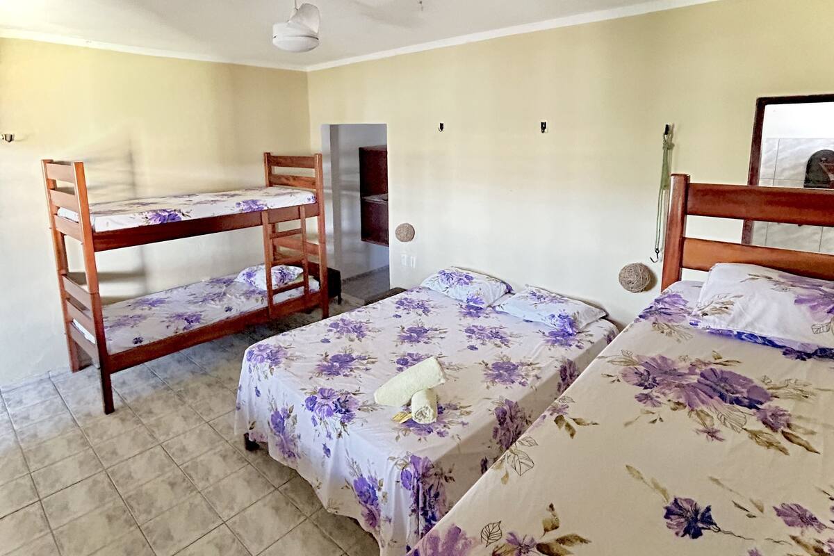 Quarto de dormitório com beliches, ventilador de teto e piso ladrilhado.