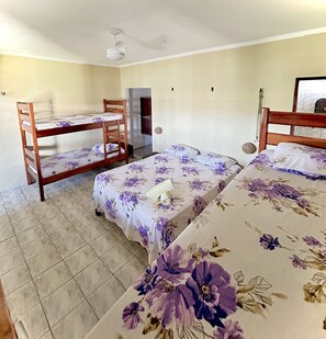 Une chambre de dortoir avec des lits superposés, un ventilateur de plafond et un sol carrelé.