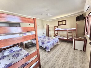 Une chambre de dortoir avec des lits superposés, un ventilateur de plafond, un petit bureau et un miroir.