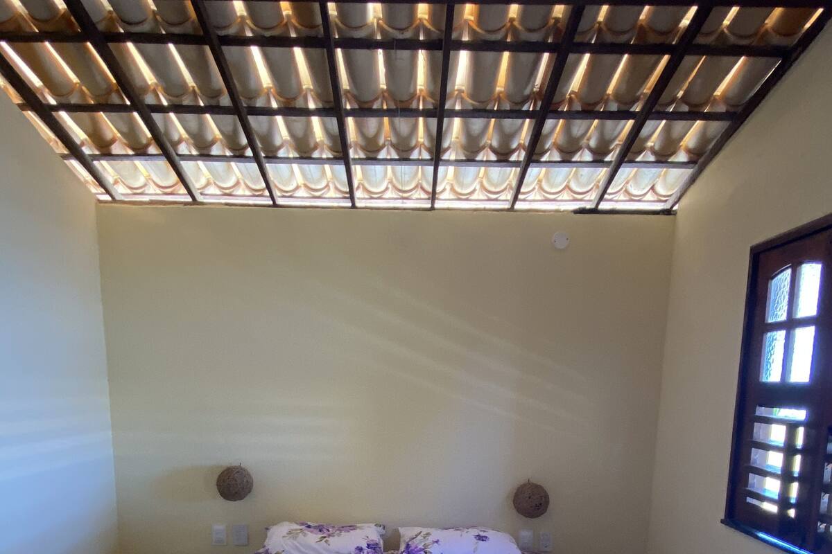 Uma cama bem arrumada com roupa de cama floral, uma cabeceira de madeira e uma janela com vista.