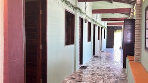 Un pasillo con suelo de baldosas, puertas de madera y techo alicatado.