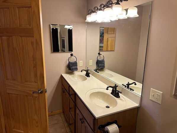 A bathroom with two sinks, a large mirror, and a wooden door.