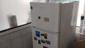 Une cuisine de taille réduite, avec un réfrigérateur blanc, des murs carrelés et une fenêtre donnant sur un paysage agréable.
