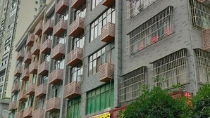 Un edificio de varios pisos con balcones, un escaparate con letreros y un toldo verde.