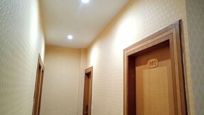 Un pasillo estrecho con puertas de madera, una de las cuales tiene una placa con un número.