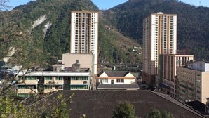 Un edificio alto con varios pisos, rodeado de un paisaje montañoso.