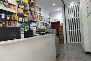 A reception area with a counter, shelves stocked with various items, a door, and a tiled floor. - YJNYBG (Yanjin)