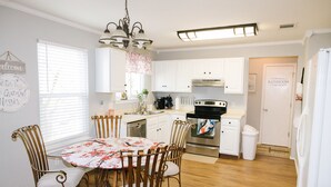 Una cocina con armarios blancos, horno de acero inoxidable y una mesa de comedor con sillas.