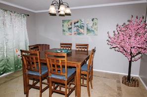 Uma sala de jantar com mesa e cadeiras de madeira, um candelabro e obras de arte na parede.