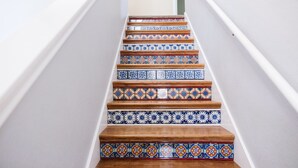 Una escalera con escalones de madera y baldosas de colores con diseños.