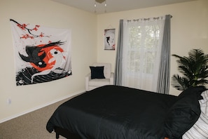 Quarto com uma cama grande, uma cadeira, um tapeçário e uma janela com cortinas.