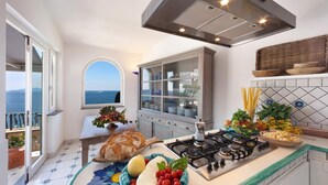 A kitchen with a view of the sea, a stove, a dining table with bread, and a fruit bowl. - Villa dei Sogni in Massa Lubrense (Massa Lubrense)