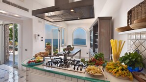 A modern kitchen with a gas stove, a view of the sea, and various fresh ingredients on the counter. - Villa dei Sogni in Massa Lubrense (Massa Lubrense)