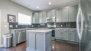 A modern kitchen with grey cabinetry, a stainless steel refrigerator, a built-in oven, and a microwave.
