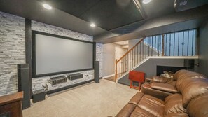 A home theater room with a large screen, a staircase, and a leather sofa. - Beautiful 3 bedroom home with theater! (Littleton)