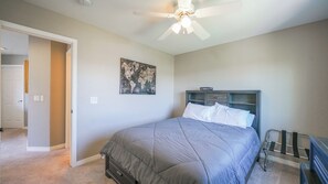 A bedroom with a bed, a ceiling fan, a wall art piece, and a door leading to another room. - Beautiful 3 bedroom home with theater! (Littleton)